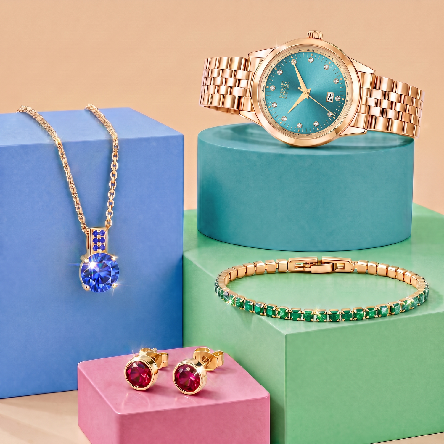 Luxe Crystal Collection by Badgley Mischka New York, featuring Crystals by Swarovski - gold sapphire necklace, emerald tennis bracelet, turquoise dial watch, and ruby bezel stud earrings on color-tinted studio risers